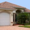 a generic one story florida home with garage, palm trees and a clear blue sky
