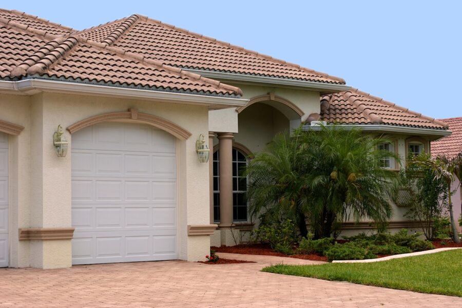 a generic one story florida home with garage, palm trees and a clear blue sky